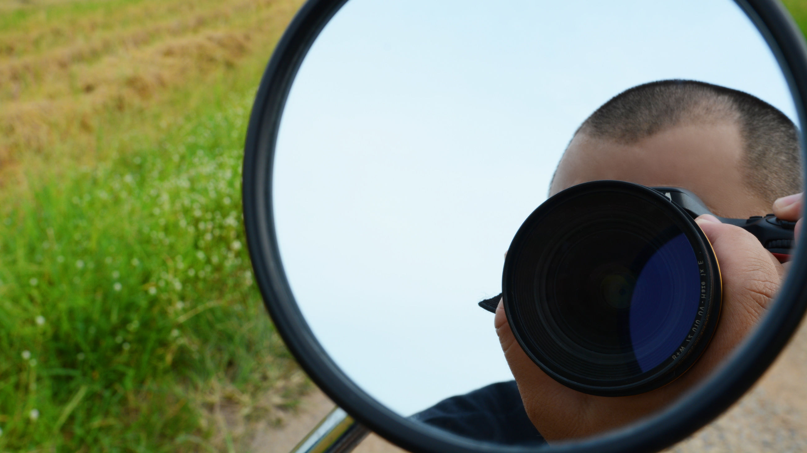 The reflection of a man capturing the nature scene on the scooter with black shirt